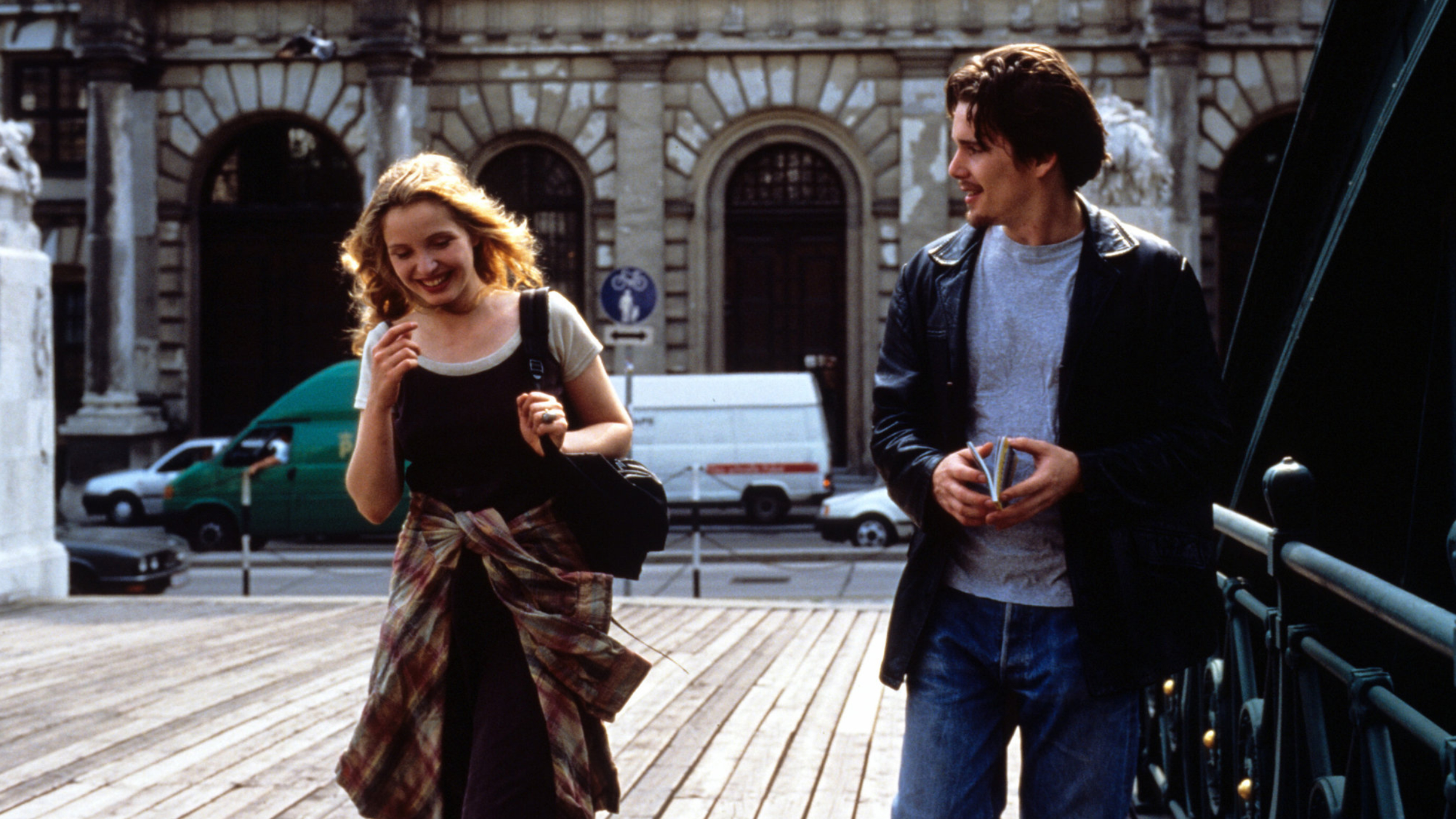Filmstill of Julie Delpy and Ethan Hawke crossing the Zollamtssteg in Vienna. Delpy smiling and Hawke holding a small guide.