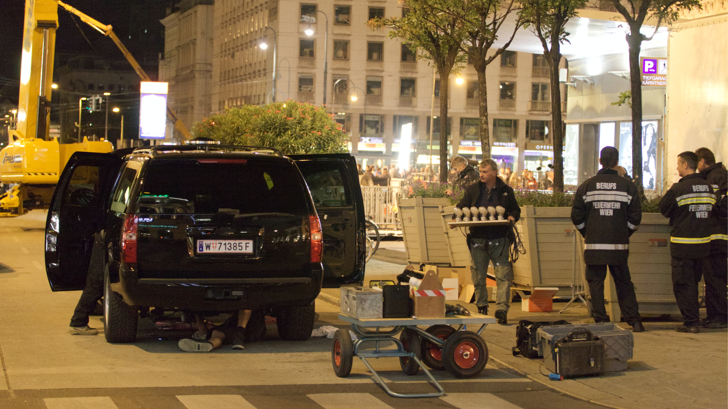 Nachts vor der Wiener Staatsoper. Die Special-Effects-Crew präpariert ein Stuntauto, das später explodieren wird.A. Vienese firefighters are watching. Die Wiener Feuerwehr steht beobachtend daneben.