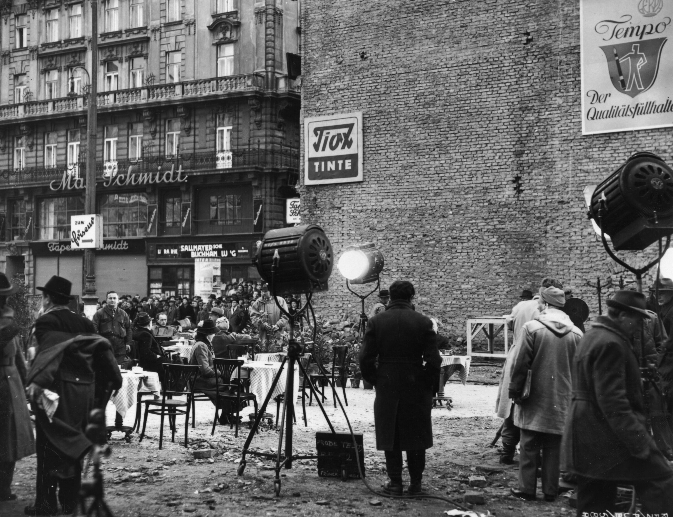 Dreh einer Szene für 'Der Dritte Mann'. In einer Baulücke stehen Kaffeehaussessel, Tische und Scheinwerfer. Im Hintergrund sind Schaulustige zu sehen.